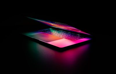 A sleek, illuminated laptop with a colorful keyboard in a dark setting.