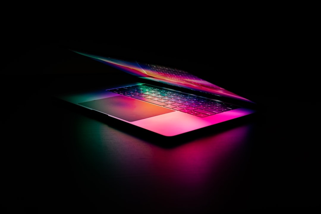 A sleek, illuminated laptop with a colorful keyboard in a dark setting.